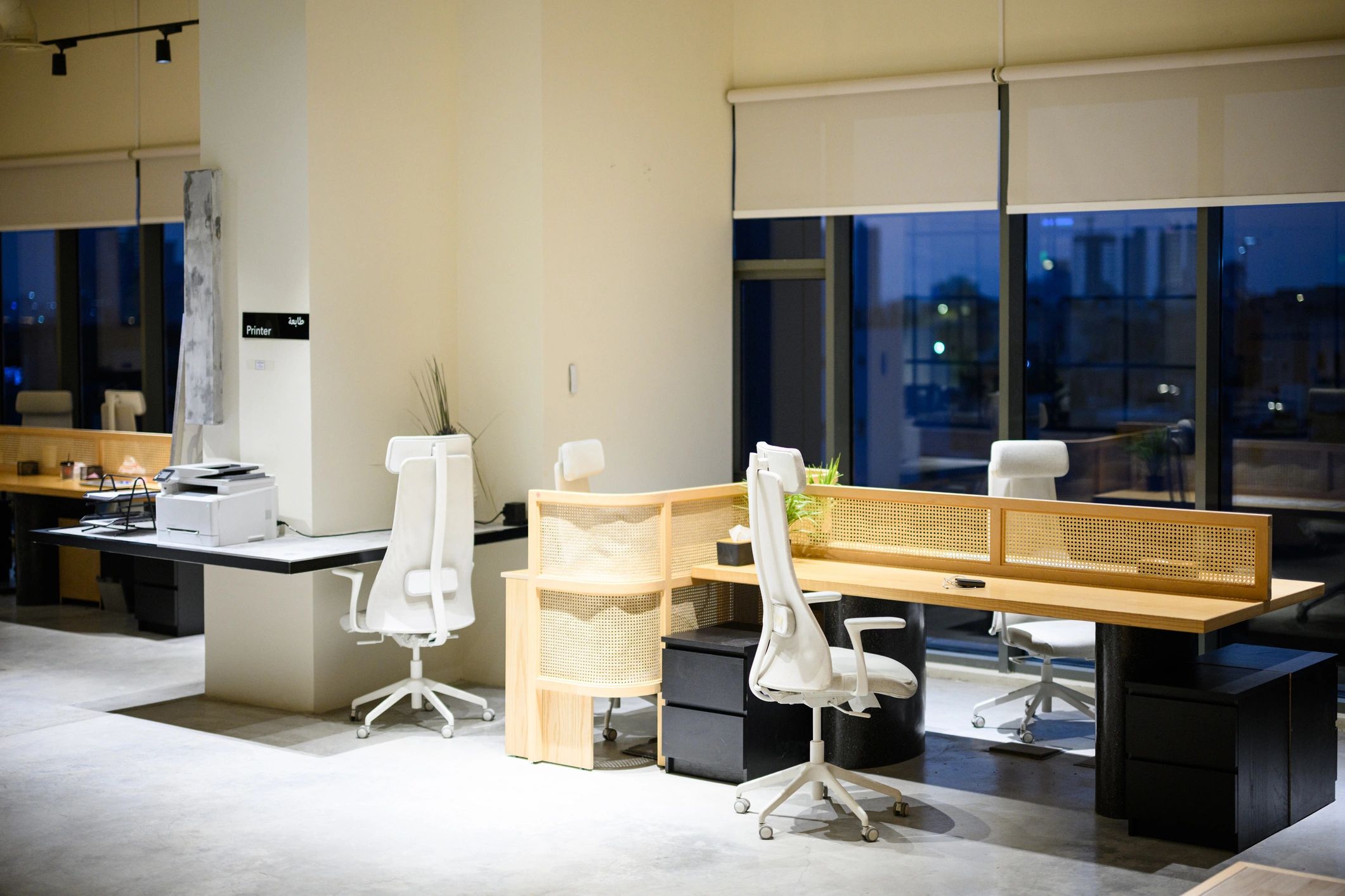 Wide shot of empty contemporary coworking office interior with shared desks and city view at night